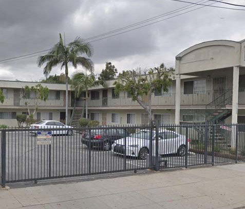 an apartment building with cars parked in a parking lot