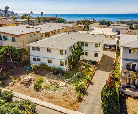 an aerial view of a group of houses with the ocean in the background