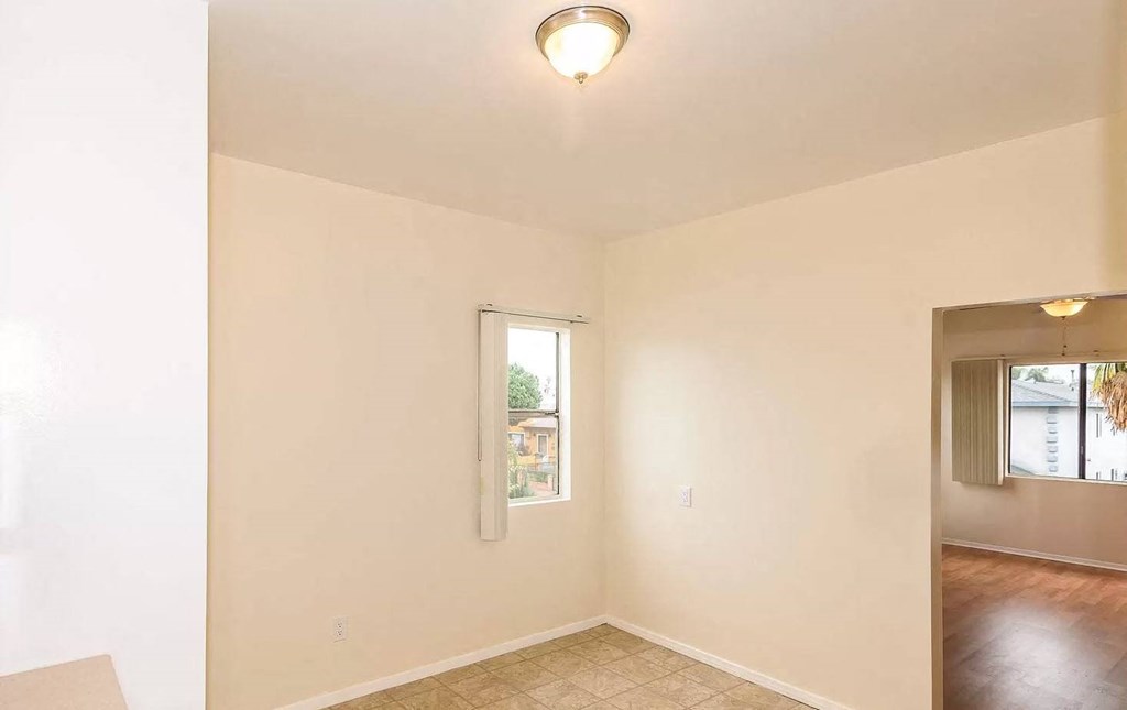 an empty living room with a window and a ceiling light