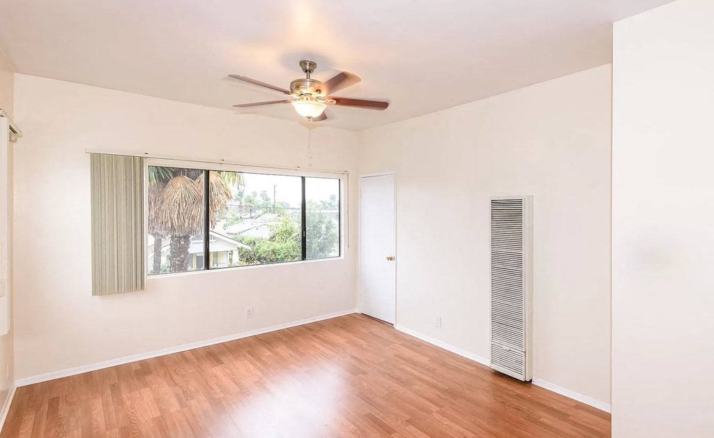 an empty living room with a window and a ceiling fan