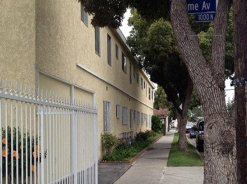 an apartment building with a white fence and a street sign