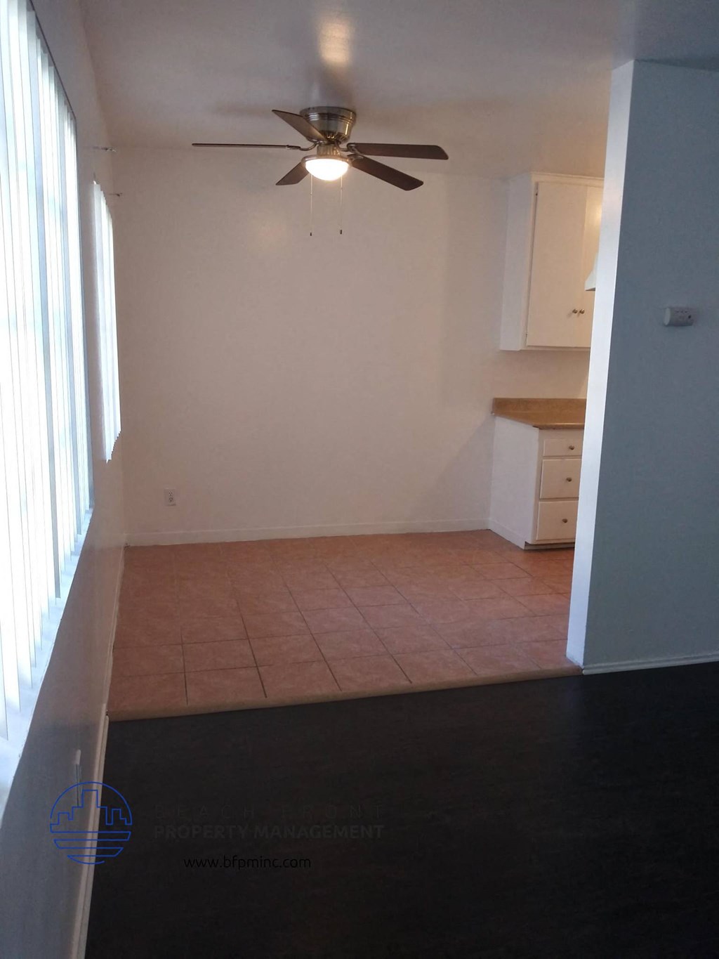 an empty kitchen with a ceiling fan and a tiled floor