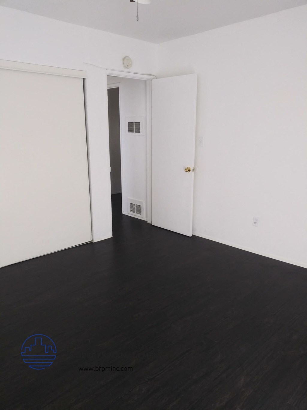 an empty room with a wood floor and white walls