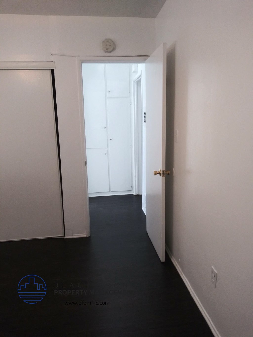 a hallway with a door open to a closet and a door to another room