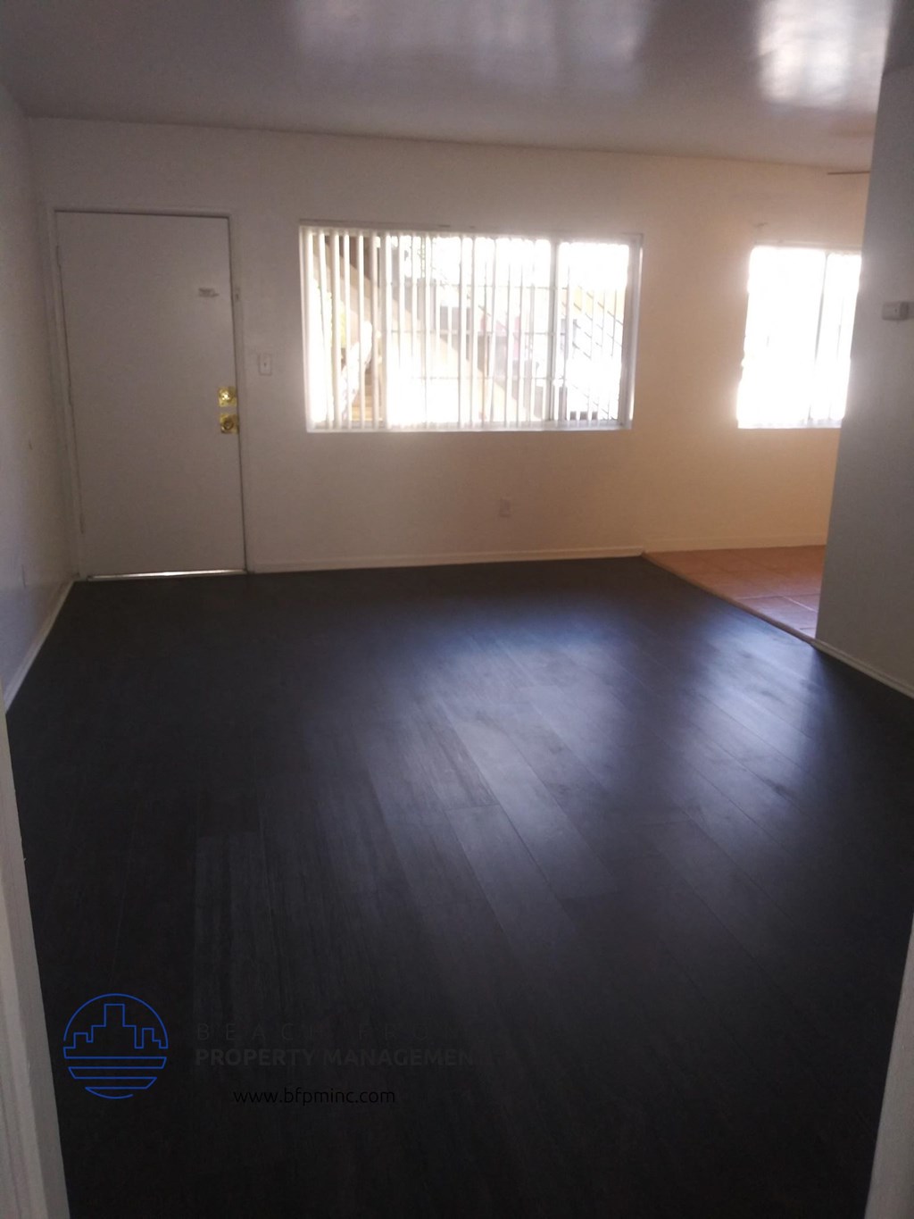 an empty living room with wood floors and a door