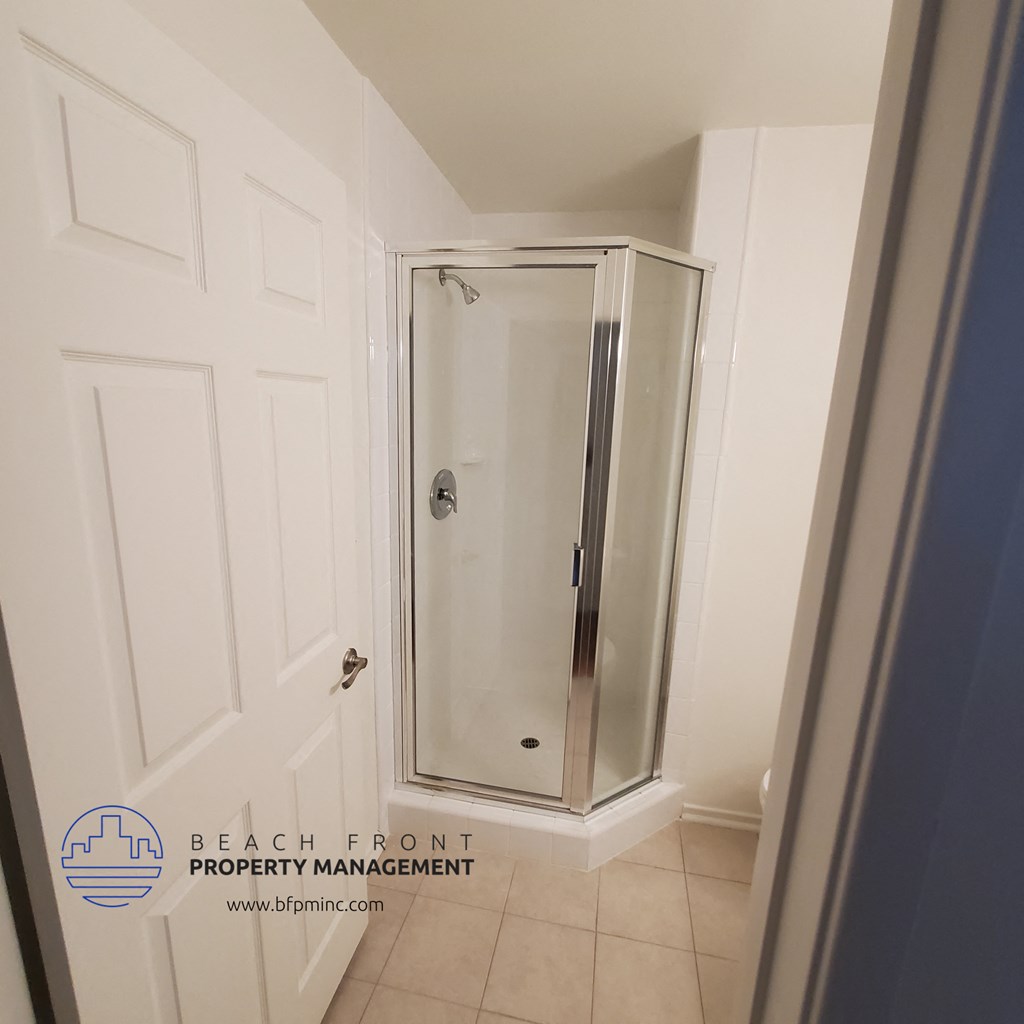 a shower stall in a small bathroom with a white door