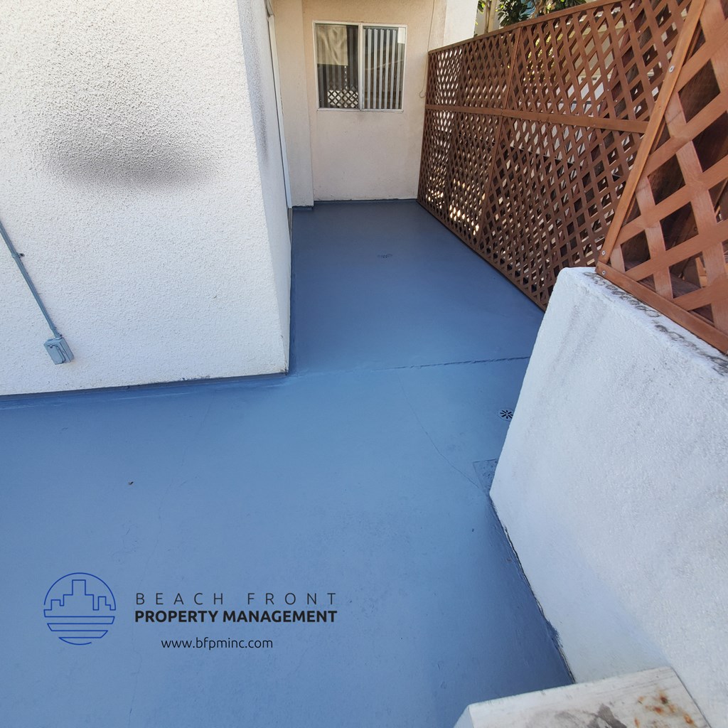 a blue painted porch with a wooden lattice fence on the right and a white wall on