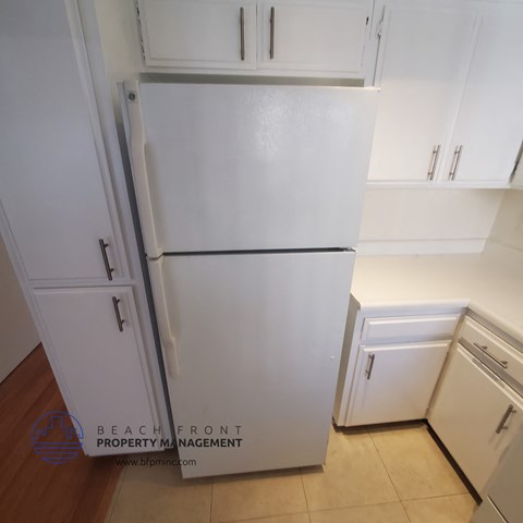 a white refrigerator in a kitchen with white cabinets
