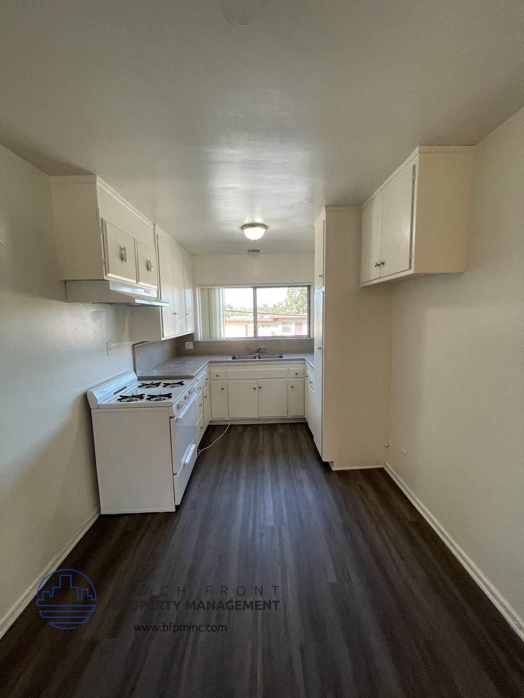 an empty kitchen with white cabinets and a window