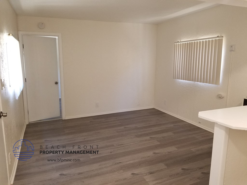 the living room of a house with wood flooring and a white door