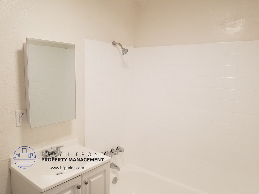 a white bathroom with a tub and a sink and a mirror