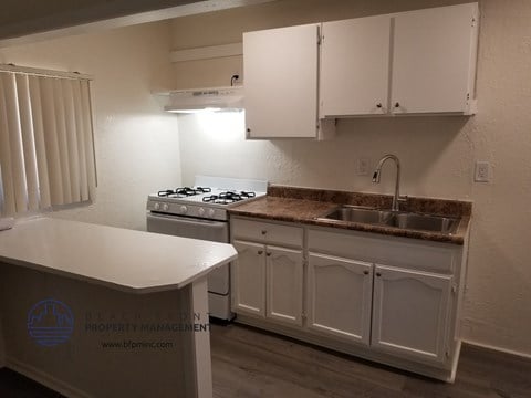 a kitchen with white cabinets and a sink and a stove