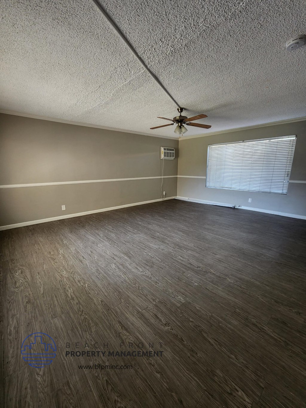 an empty living room with wood floors and a ceiling fan