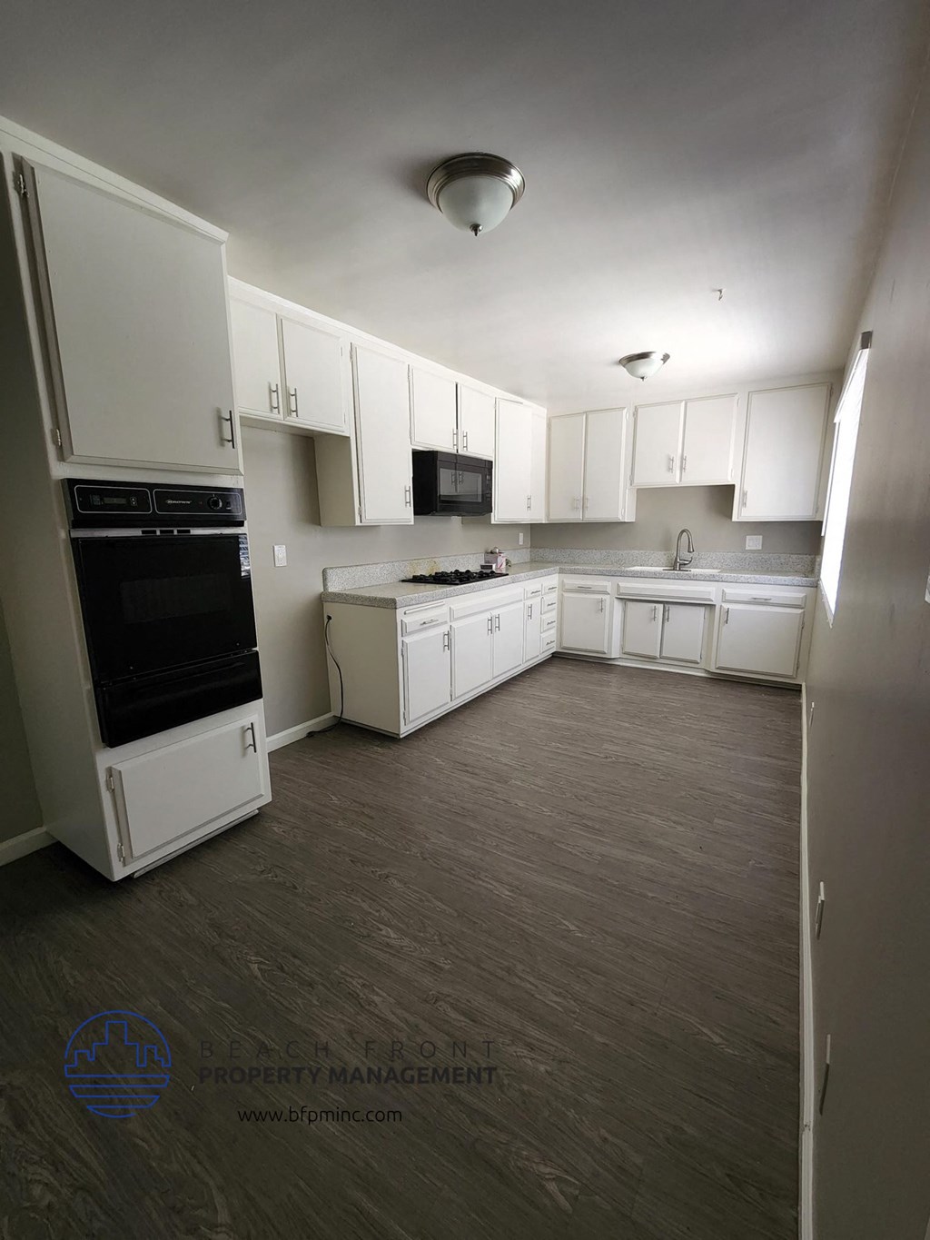 an empty kitchen with white cabinets and a wood floor