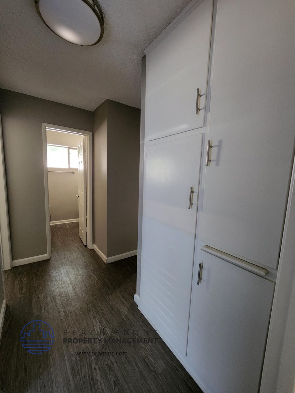 a bedroom with a white door and a hallway with a closet and a window