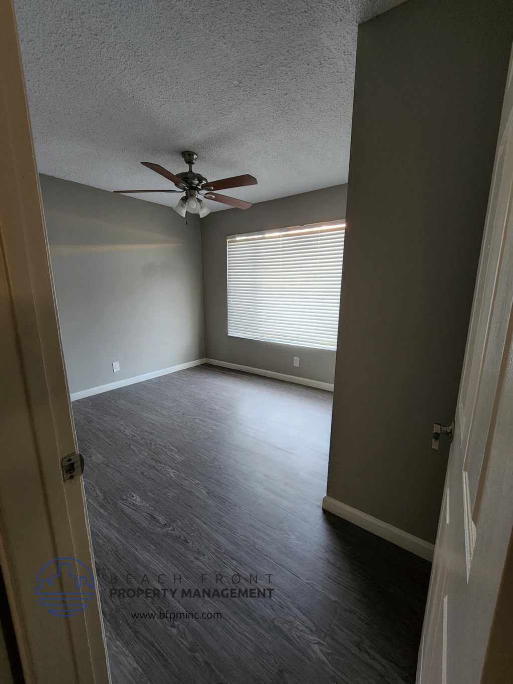an empty room with a ceiling fan and a window