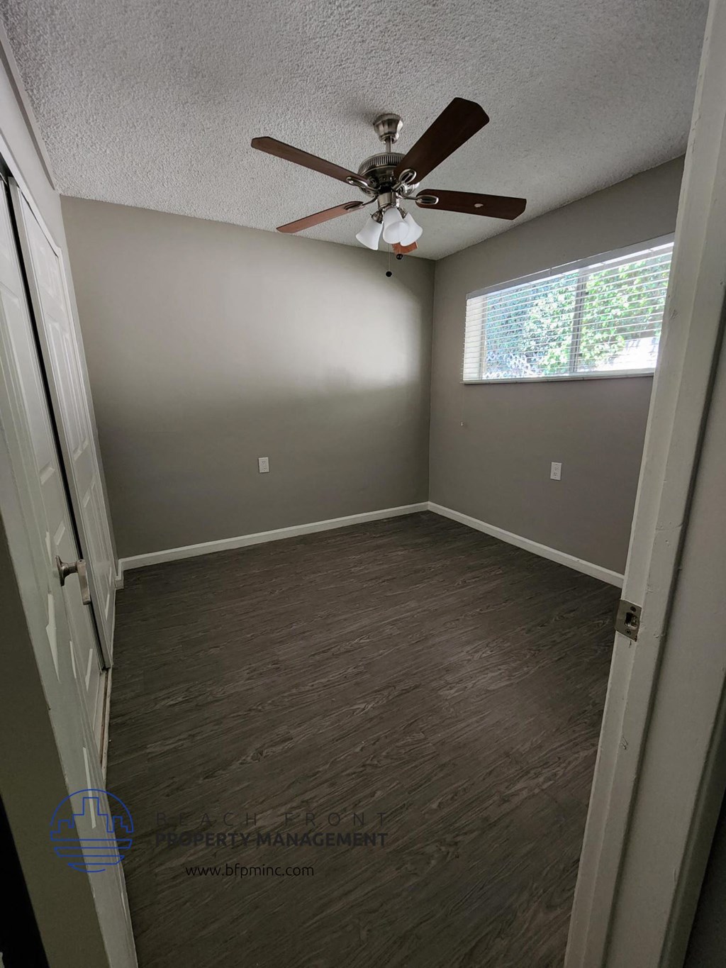 a empty room with a ceiling fan and a window