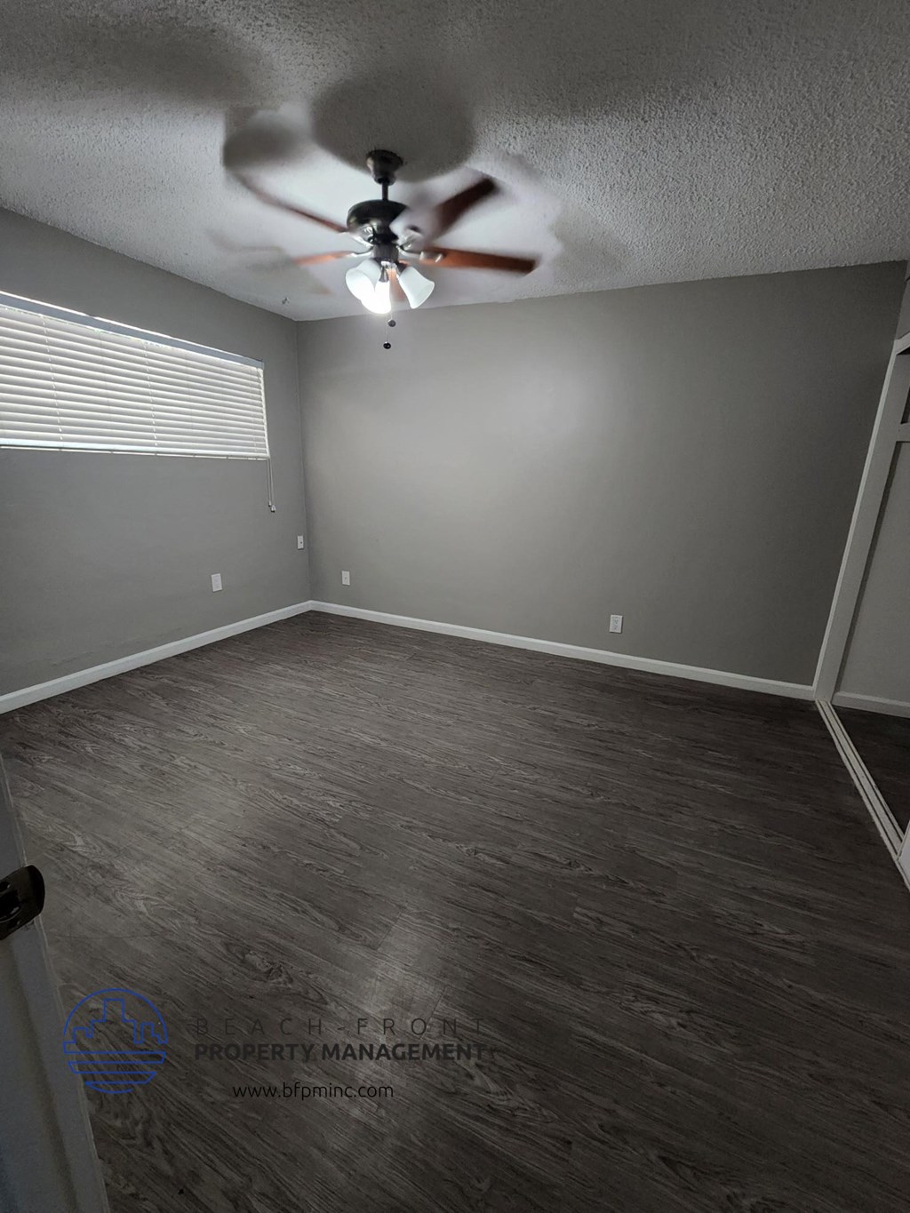 an empty room with a ceiling fan and a window