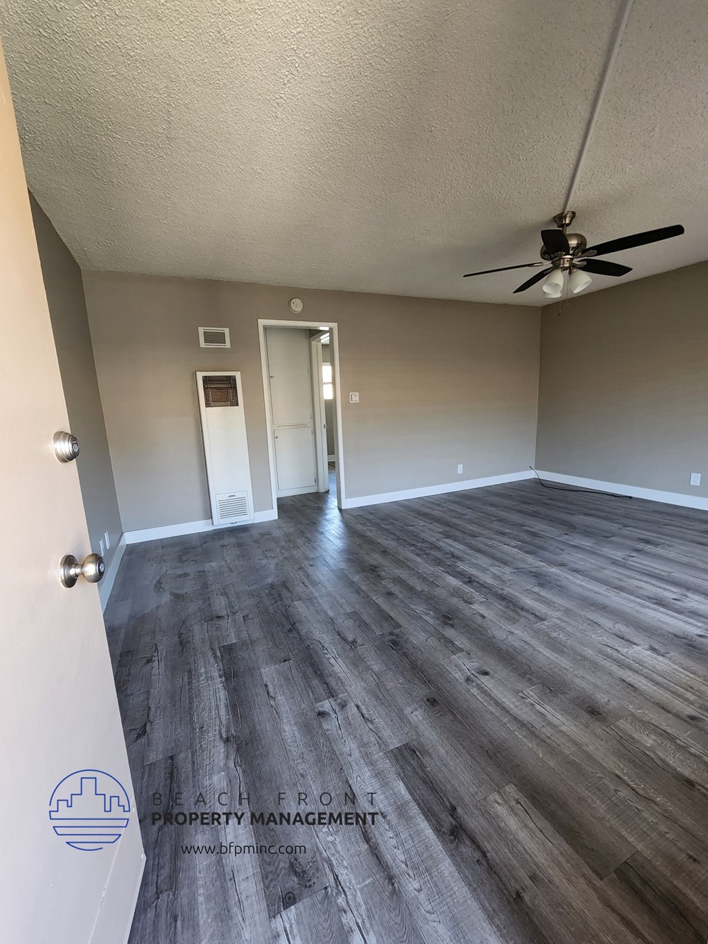 an empty living room with wood floors and a ceiling fan