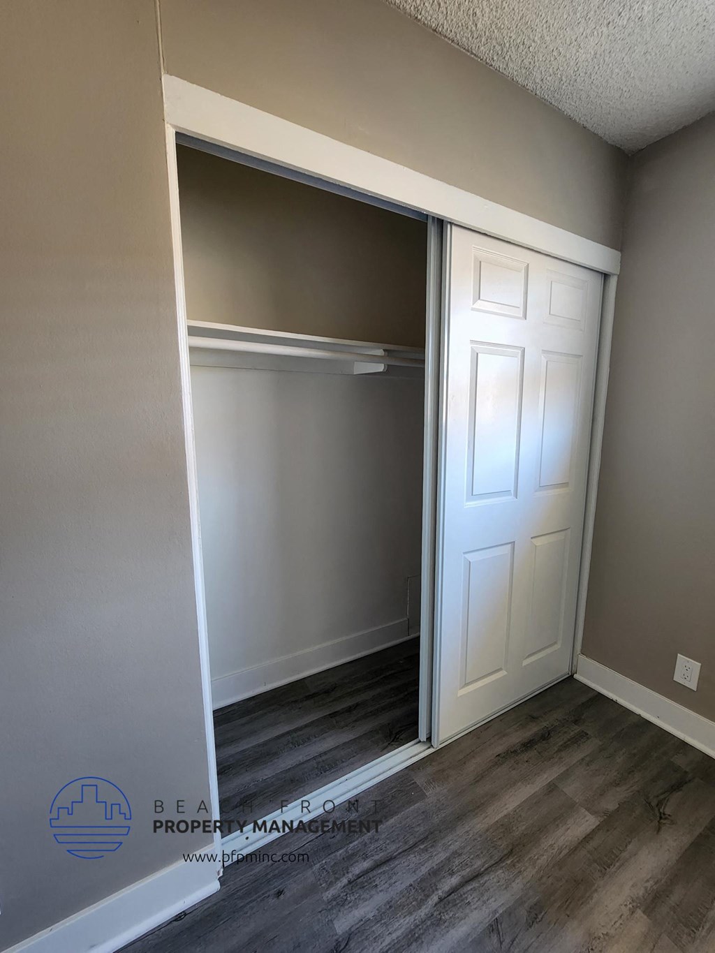 a walk in closet with a white door and wood floors