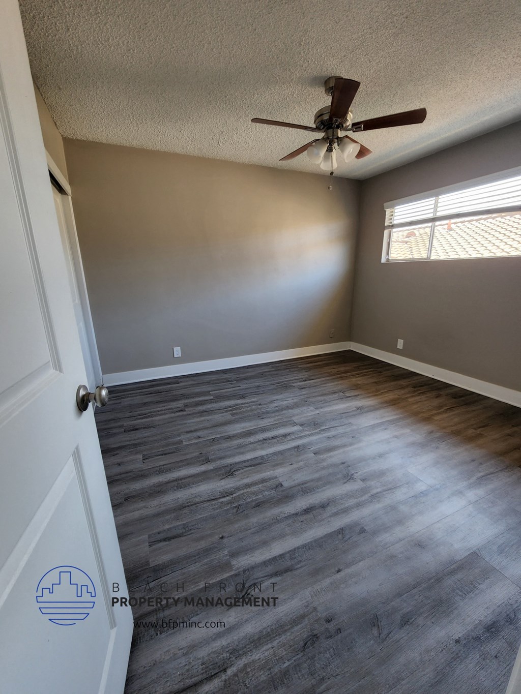 an empty bedroom with wood floors and a ceiling fan