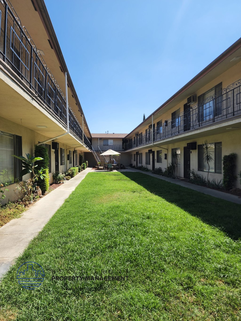 the courtyard of a hotel with a green lawn and a sidewalk