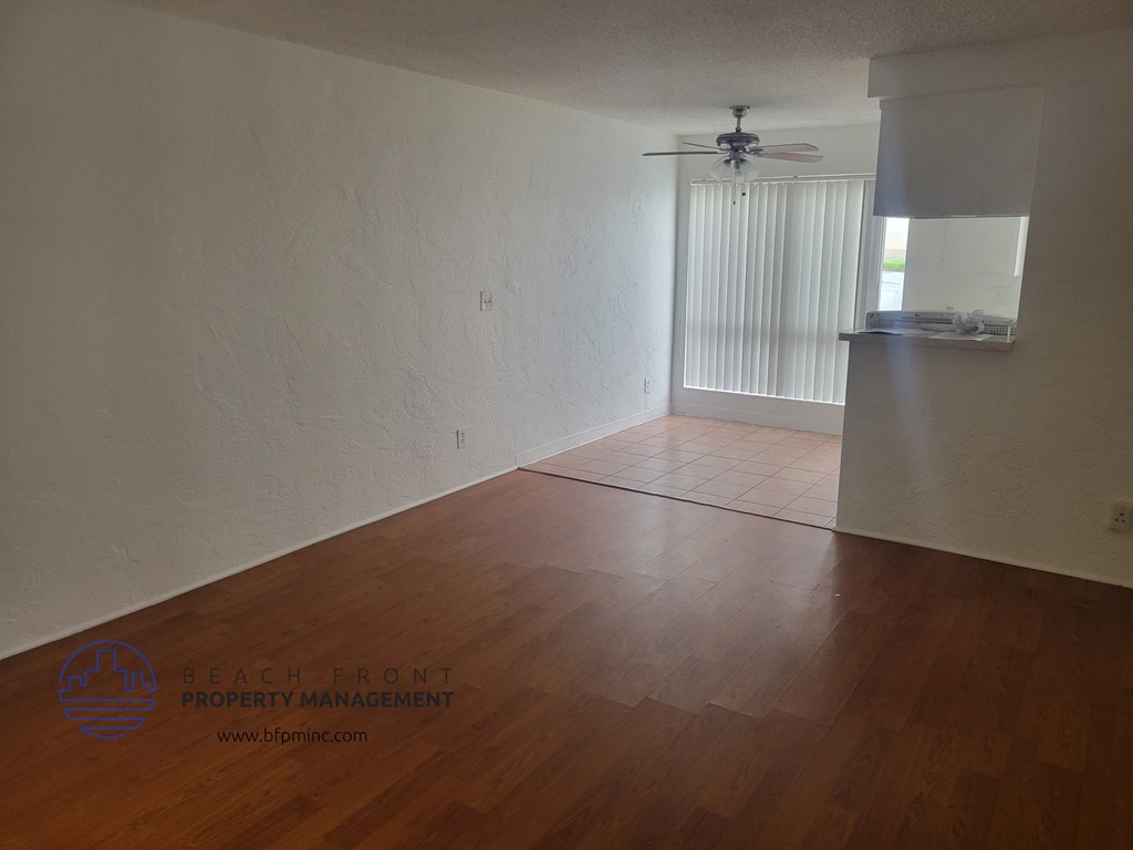 the interior of a living room with wood floors and a ceiling fan