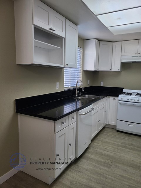 a kitchen with white cabinets and a black counter top