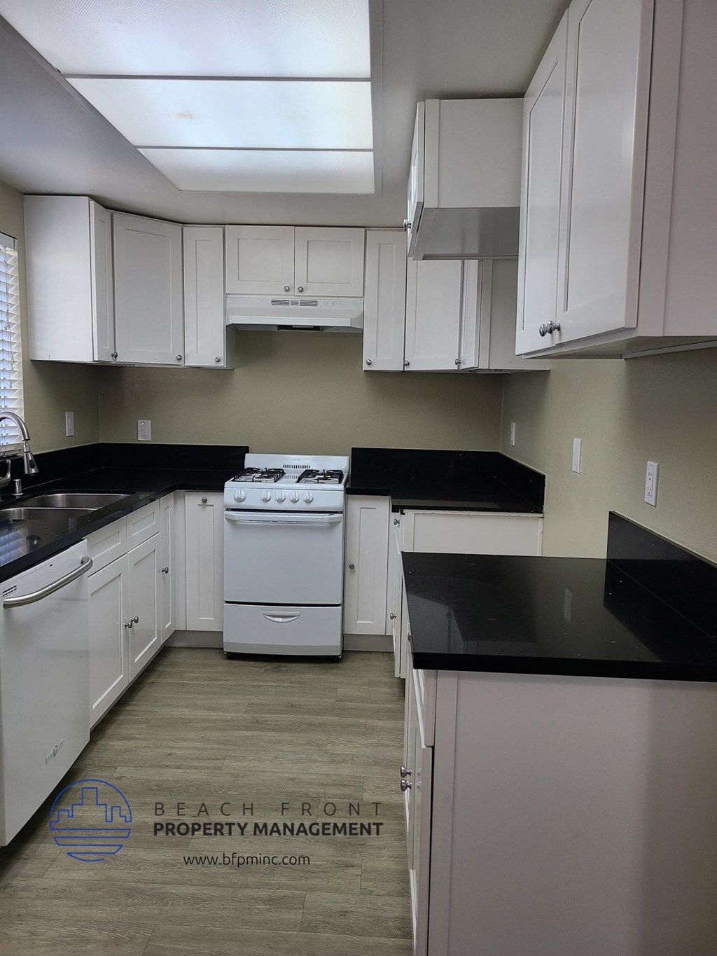 an empty kitchen with white cabinets and black counter tops