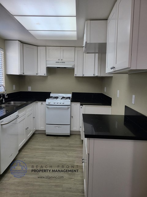 an empty kitchen with white cabinets and black counter tops