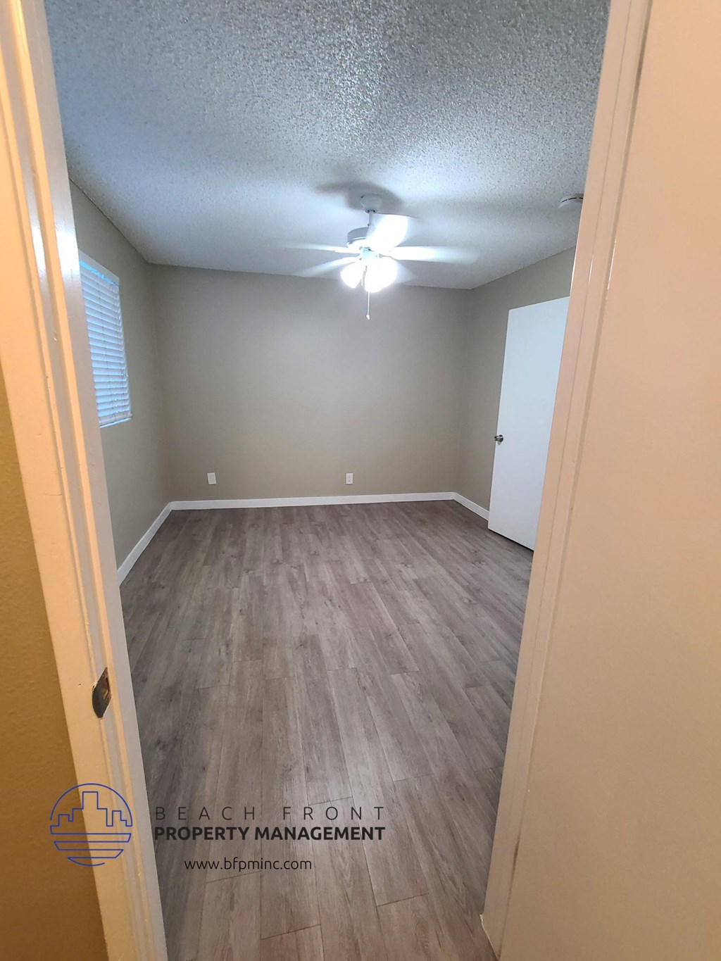 a empty room with wood floors and a ceiling fan