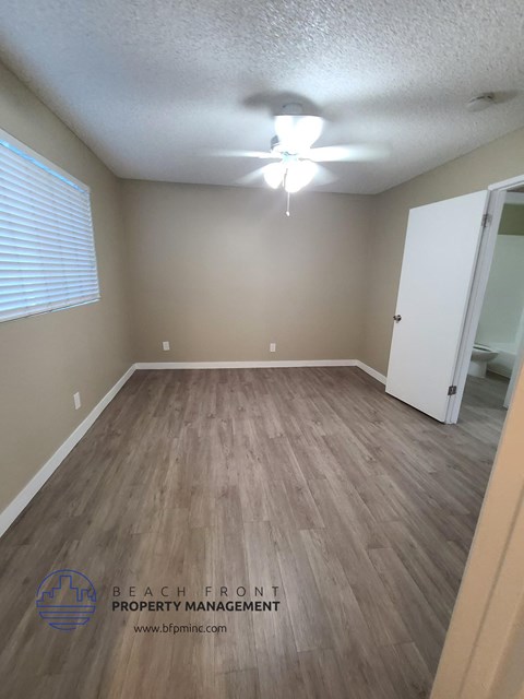 an empty room with wood flooring and a ceiling fan