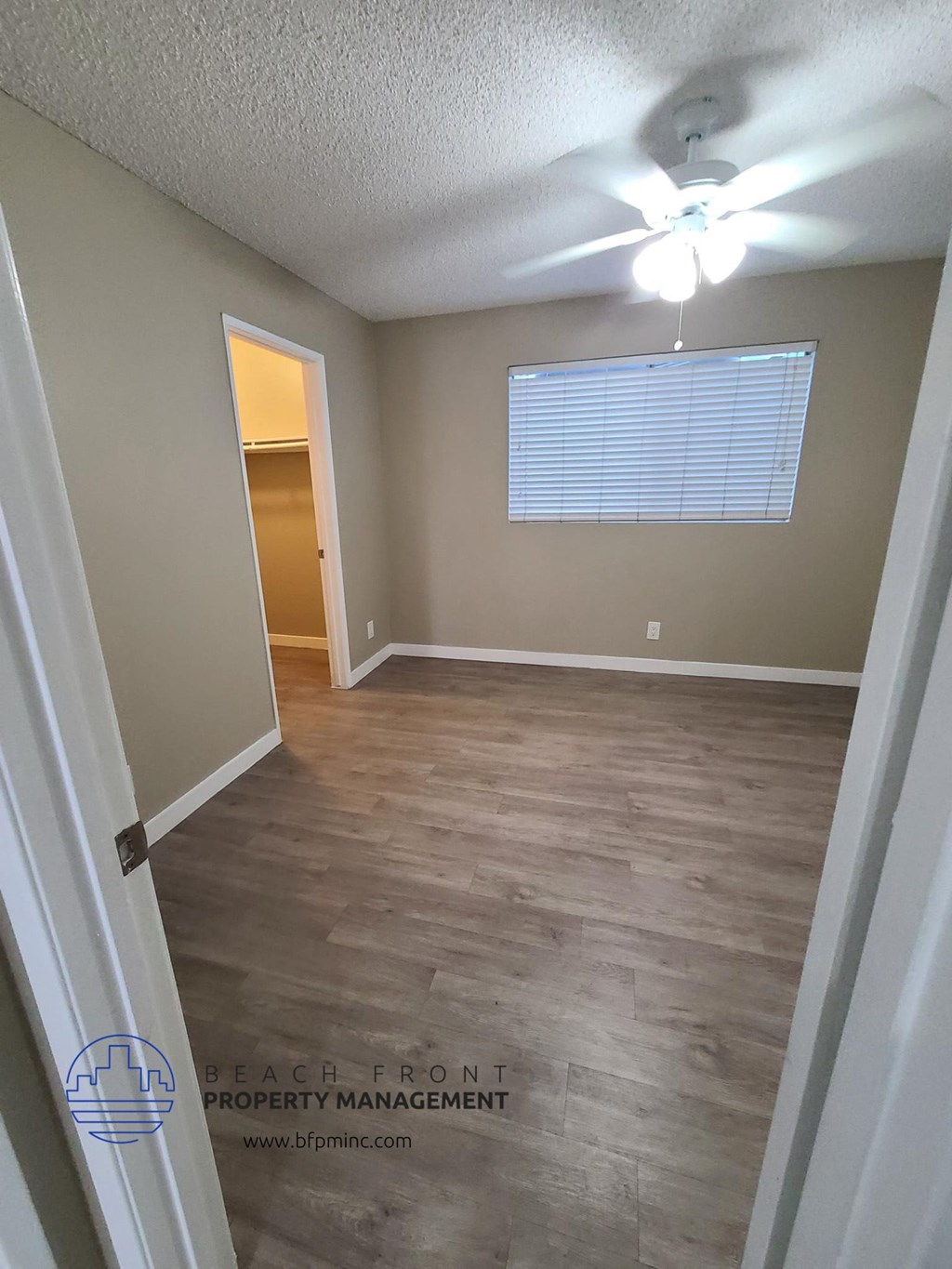an empty room with wood floors and a ceiling fan