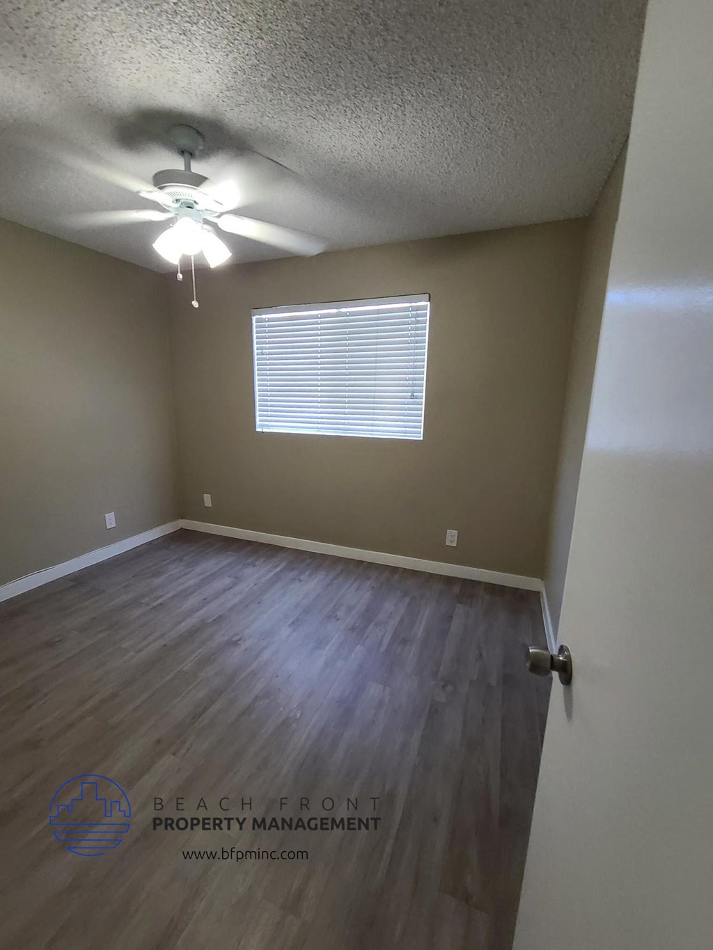 the living room of a home with wood flooring and a ceiling fan