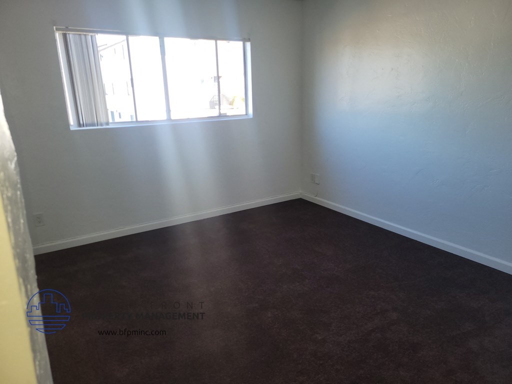an empty room with a window and a brown floor