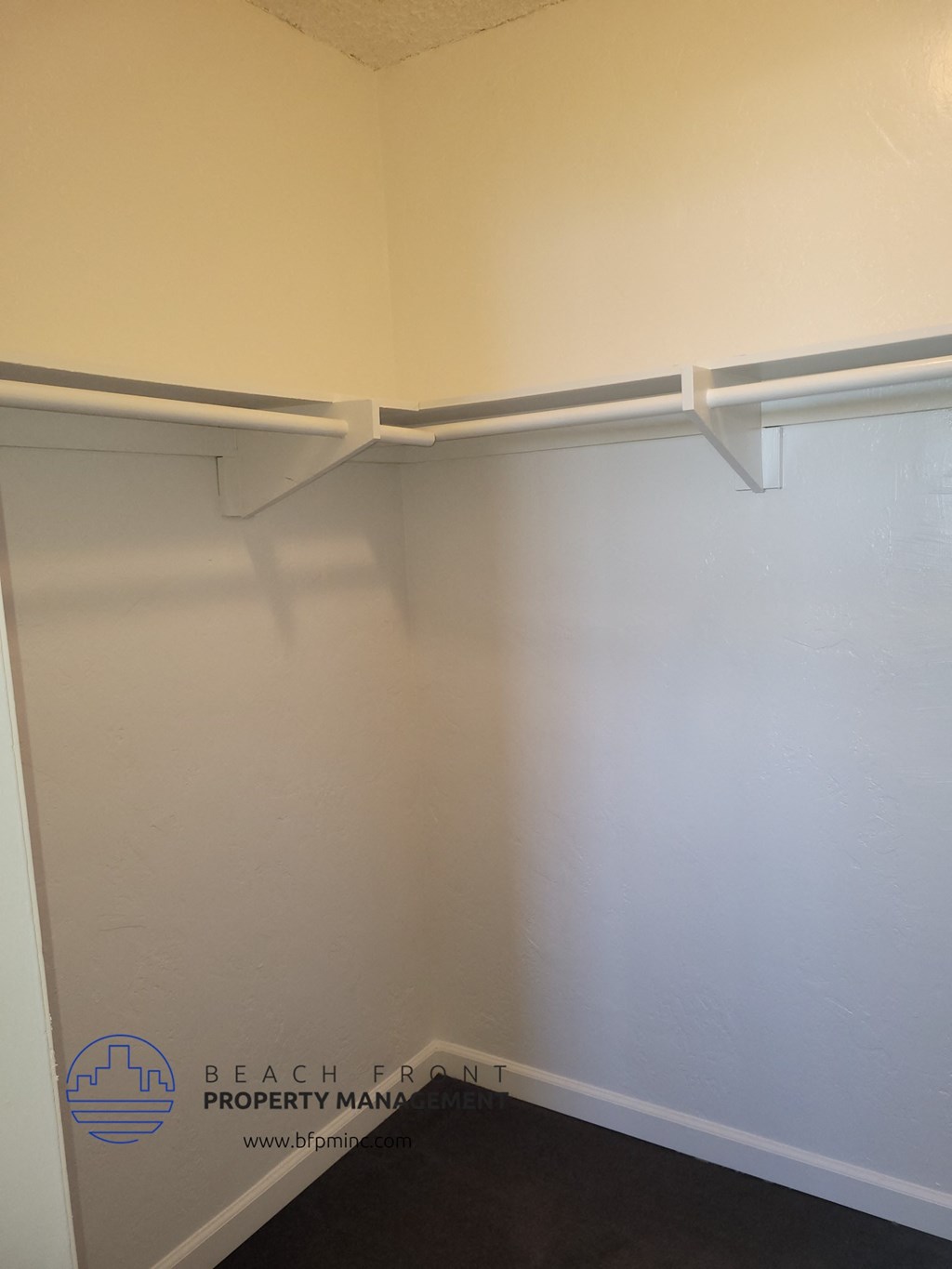 a walk in closet with white shelves and a white wall