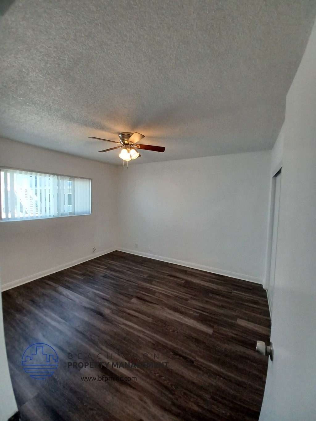 an empty room with a ceiling fan and a window