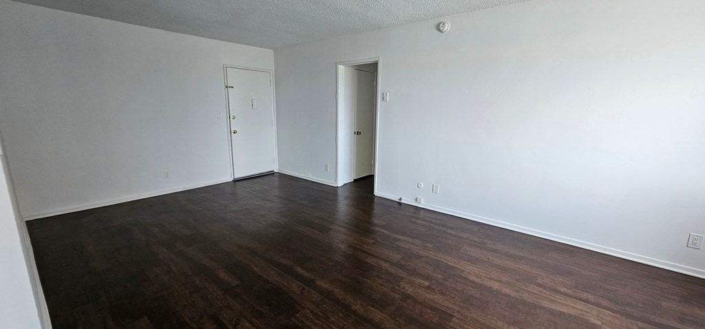 a bedroom with white walls and hardwood floors