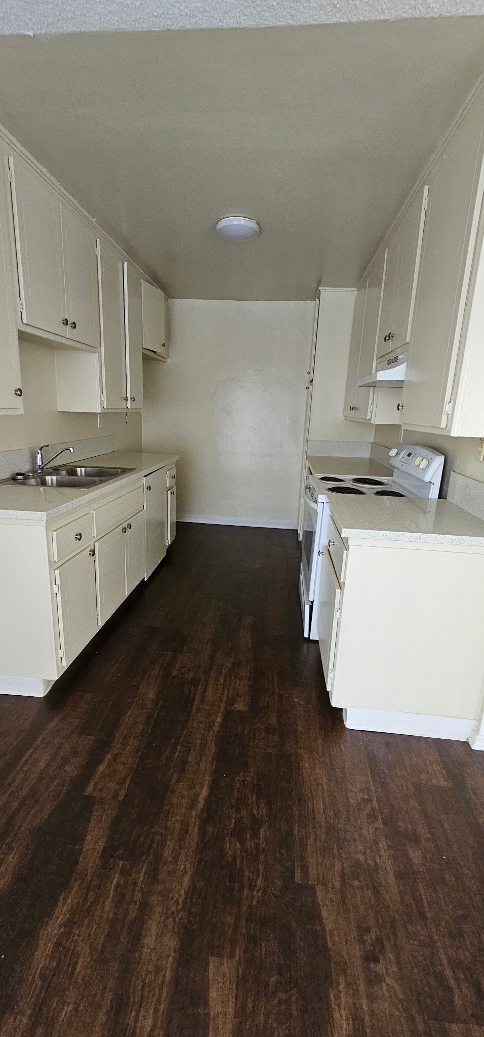 an empty kitchen with white cabinets and white appliances