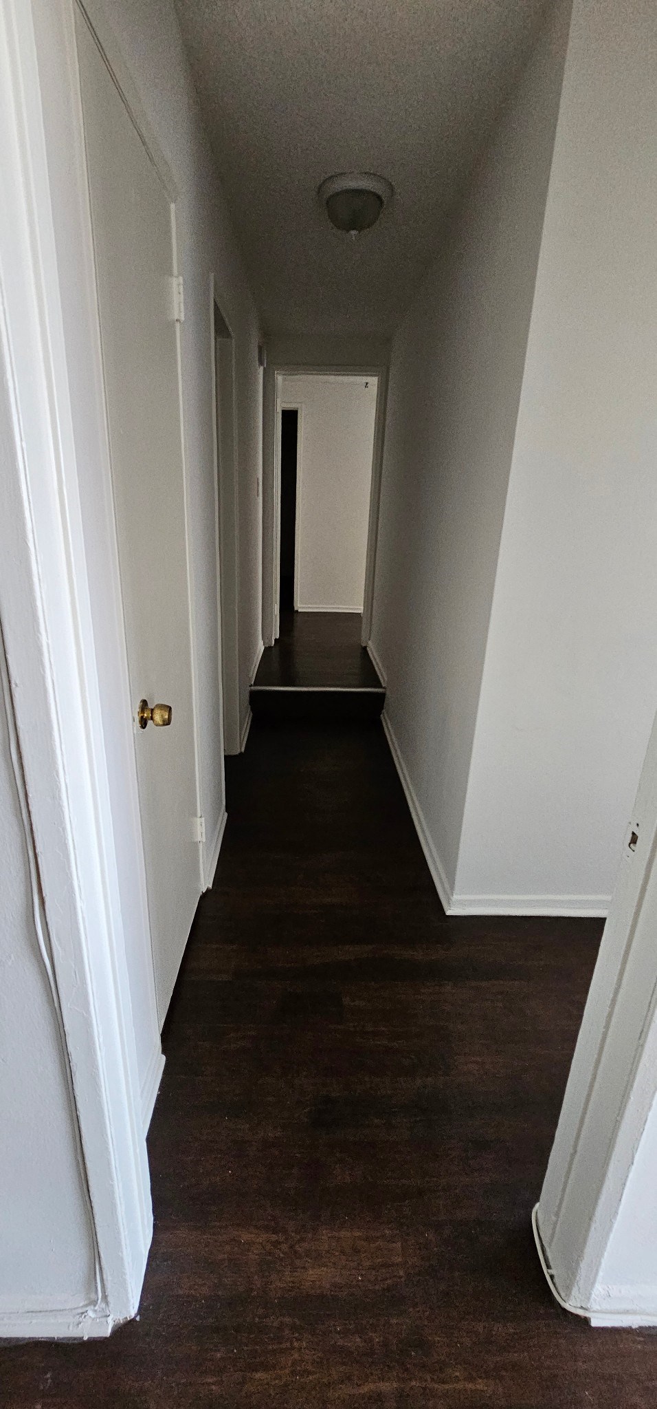 a long hallway with white walls and wood floors