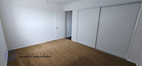 a bedroom with white walls and a carpet and two closets