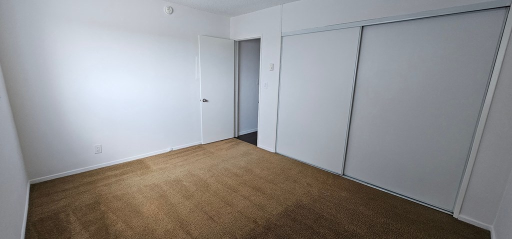 a bedroom with white walls and a brown carpet
