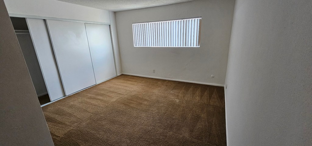 an empty bedroom with a closet and a window