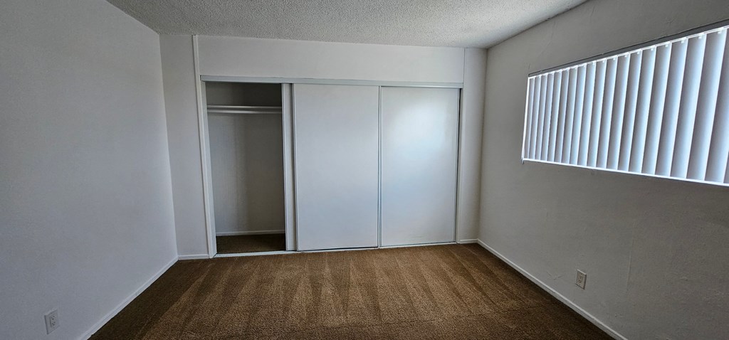 an empty bedroom with a closet and a window