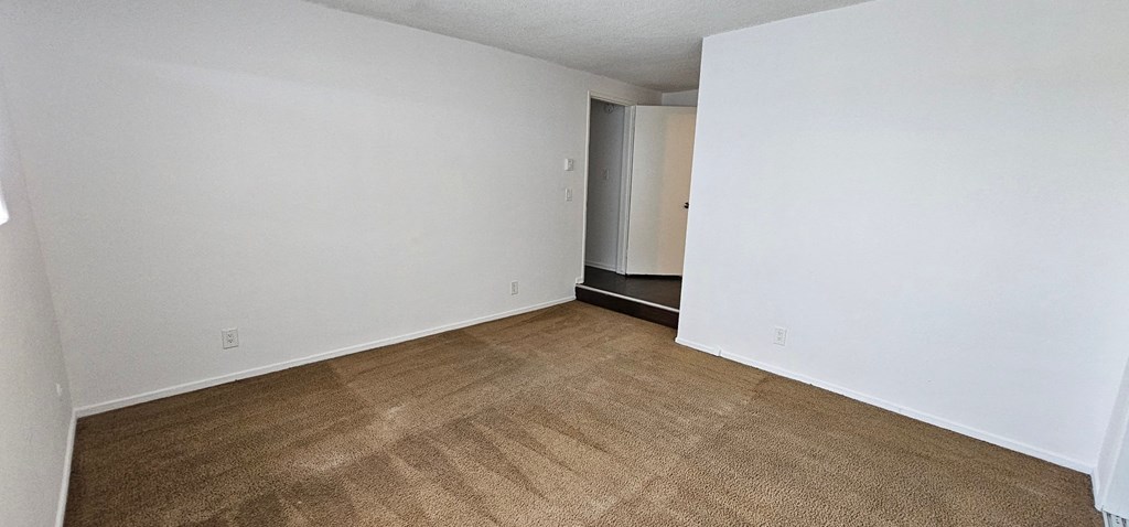 a bedroom with white walls and a beige carpet