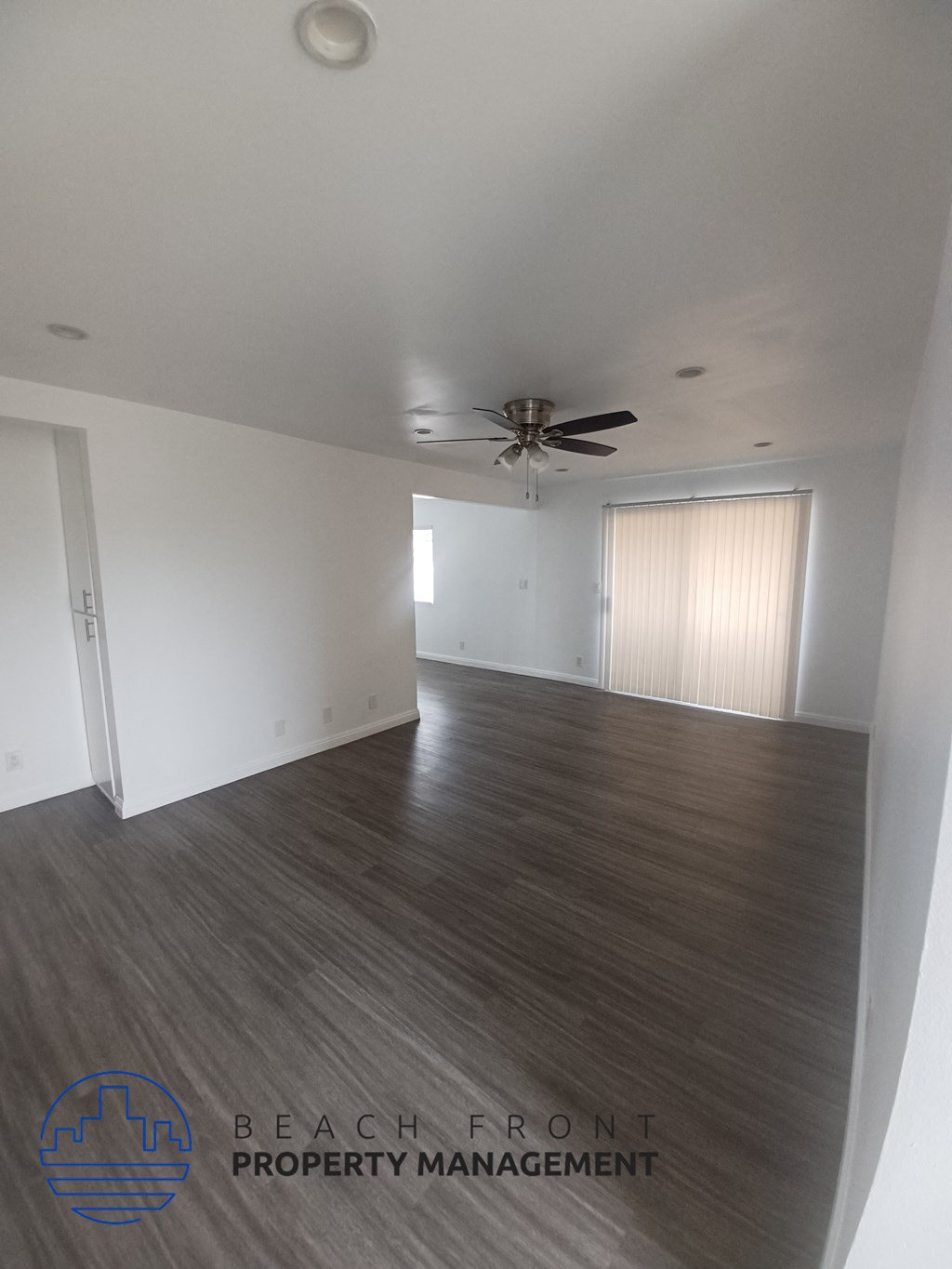 an empty living room with wood flooring and a ceiling fan
