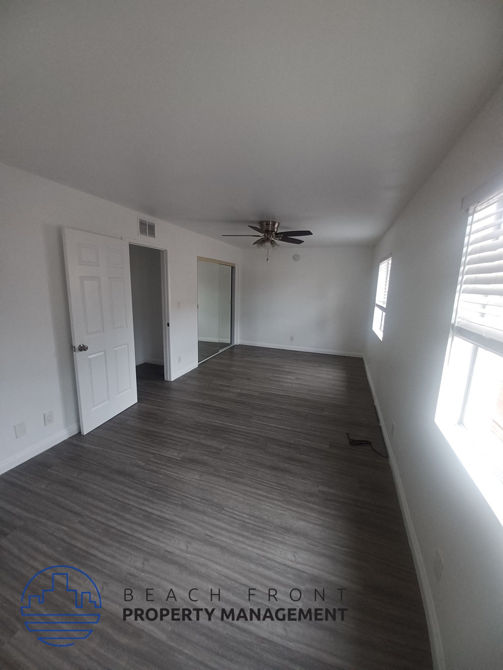 an empty living room with white walls and a ceiling fan