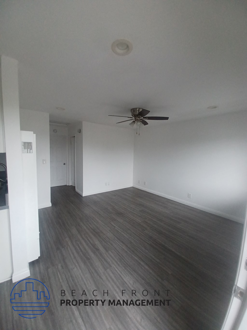 an empty living room with white walls and a ceiling fan