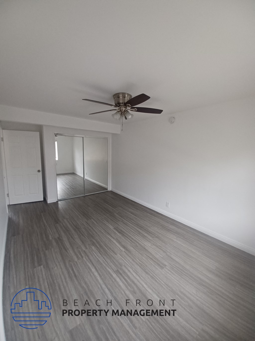 a living room with white walls and a ceiling fan