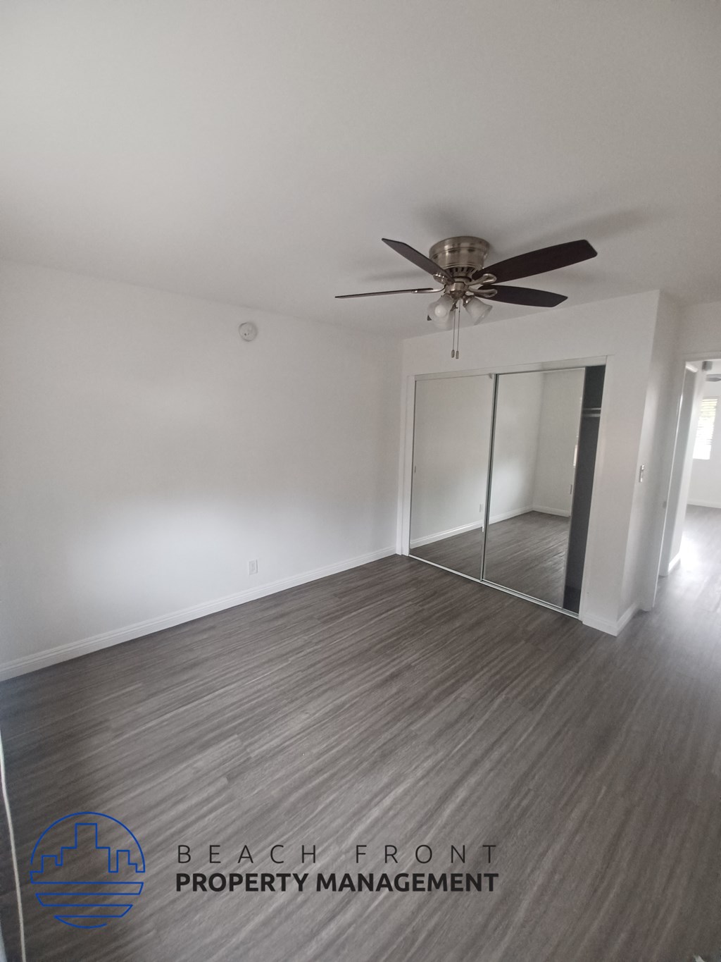 an empty living room with a ceiling fan and a mirror